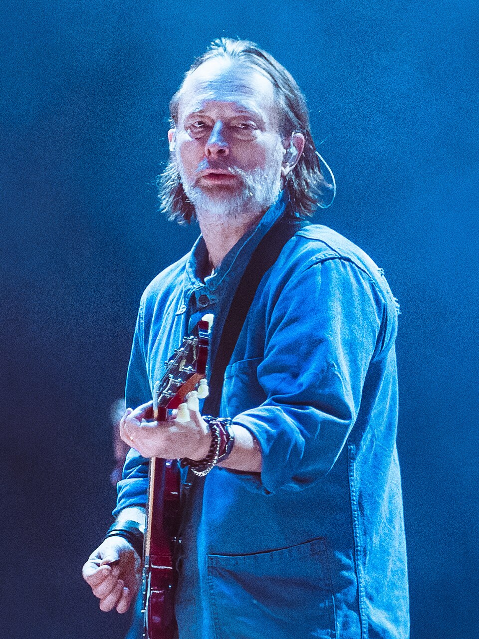Thom Yorke con la chitarra sotto una luce blu, dal vivo con i Radiohead il 24 novembre 2025