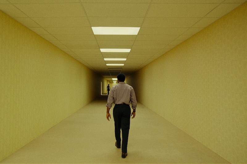 Un corridoio, una figura, nessuna uscita evidente: immagine ufficiale di Backrooms.